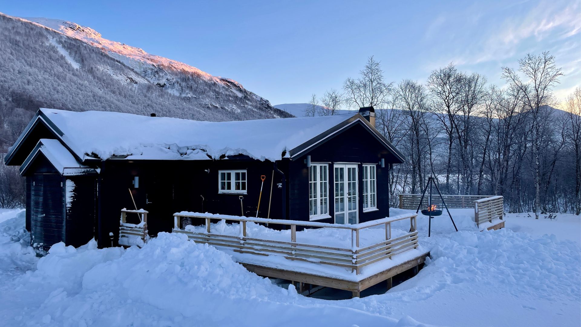 Svart fjällstuga i snö