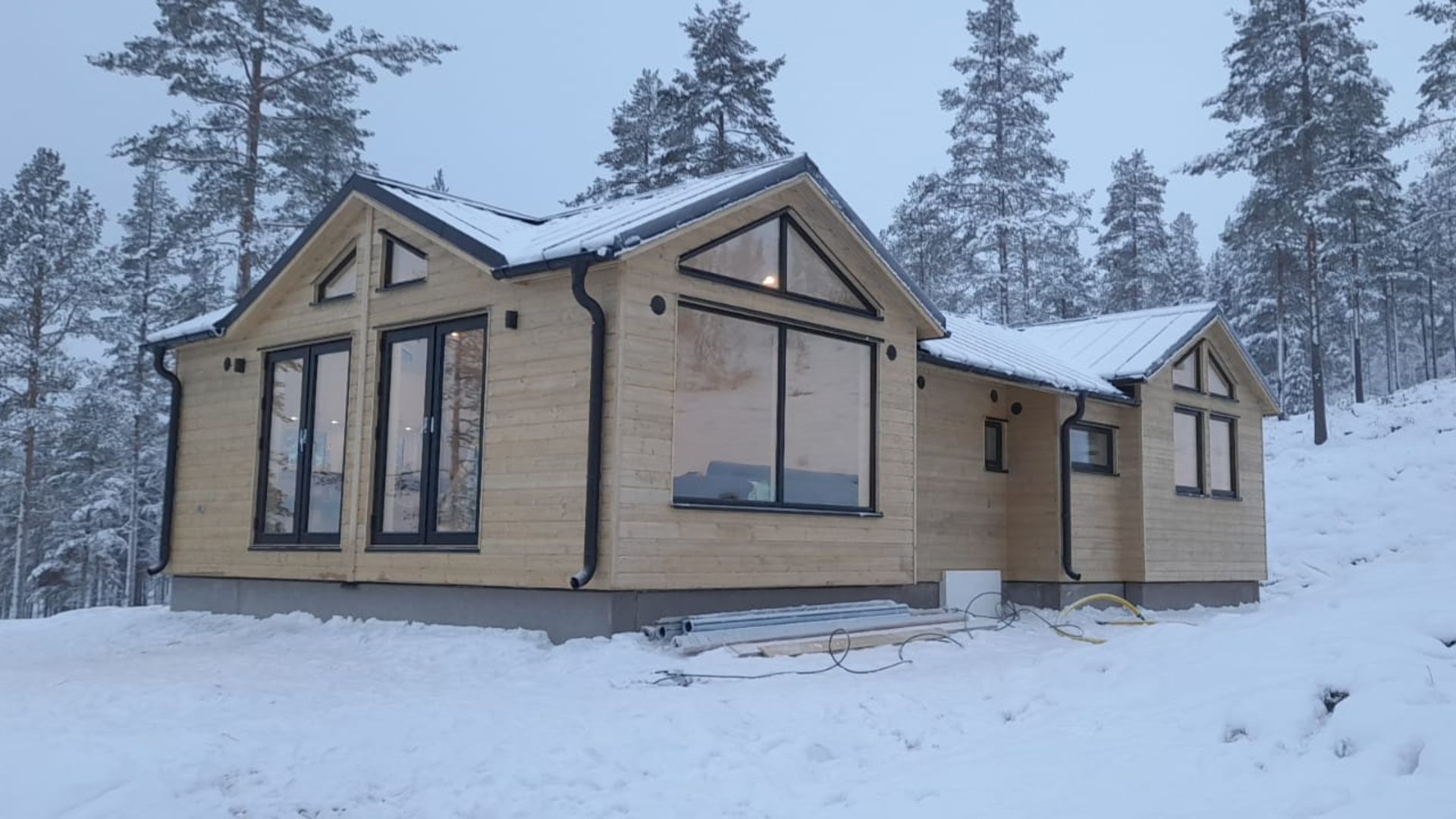 Fjällstuga exteriör med stora fönster snö
